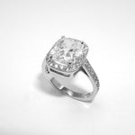 A platinum cushion cut diamond ring with a halo effect, featuring smaller diamonds set around the main diamond.