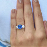 Woman wearing platinum cushion cut saphire and diamond custom designed ing 