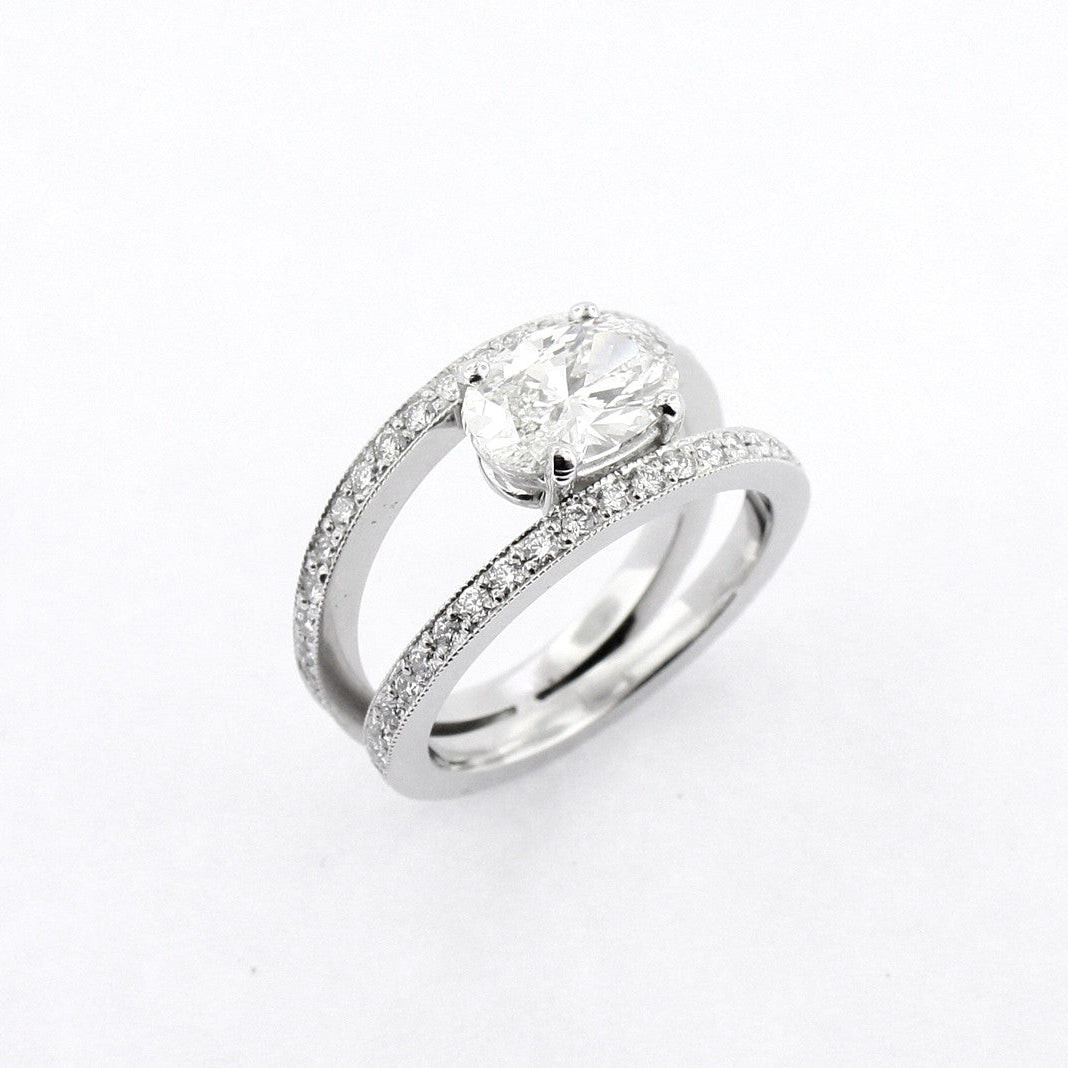 A platinum oval cut diamond ring with smaller round diamonds set in the band.