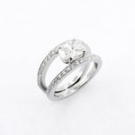A platinum oval cut diamond ring with smaller round diamonds set in the band.