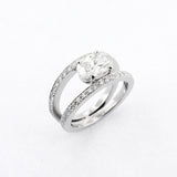 A platinum oval cut diamond ring with smaller round diamonds set in the band.