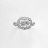 A platinum emerald cut diamond ring with an oval diamond halo on a white background.