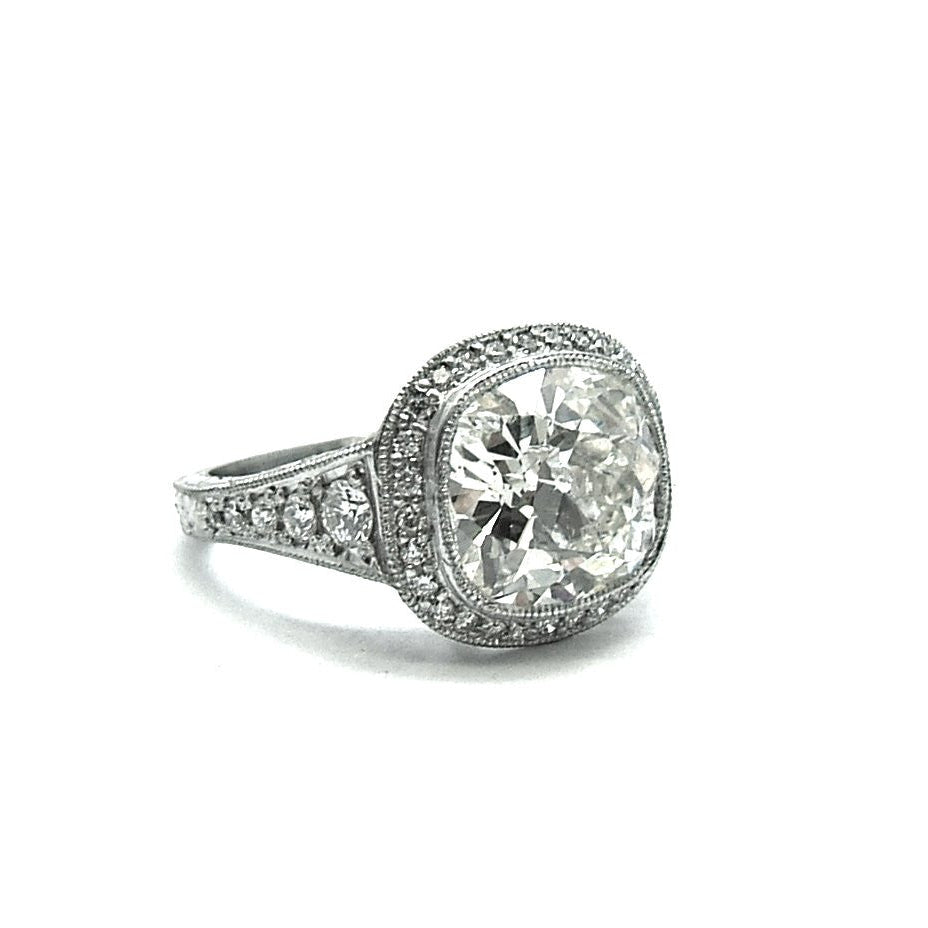 A platinum old mine cut diamond ring with a halo of smaller diamonds around the main stone.