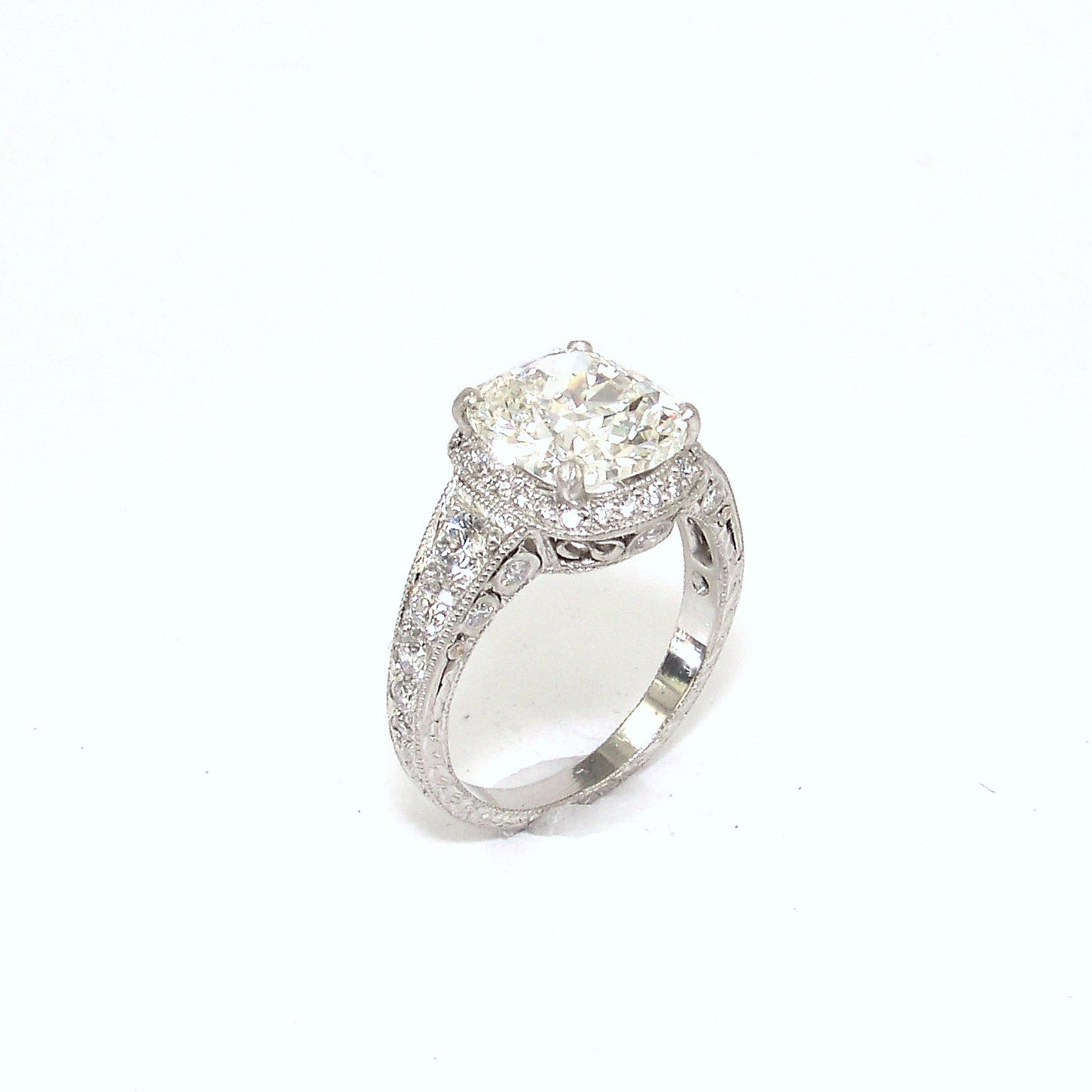 A platinum old mine cut diamond ring with a halo effect, featuring a larger diamond in the center surrounded by smaller ones set in a platinum band.