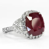 A ring with a large red ruby center stone, flanked by two half-moon shaped diamonds on a platinum band.