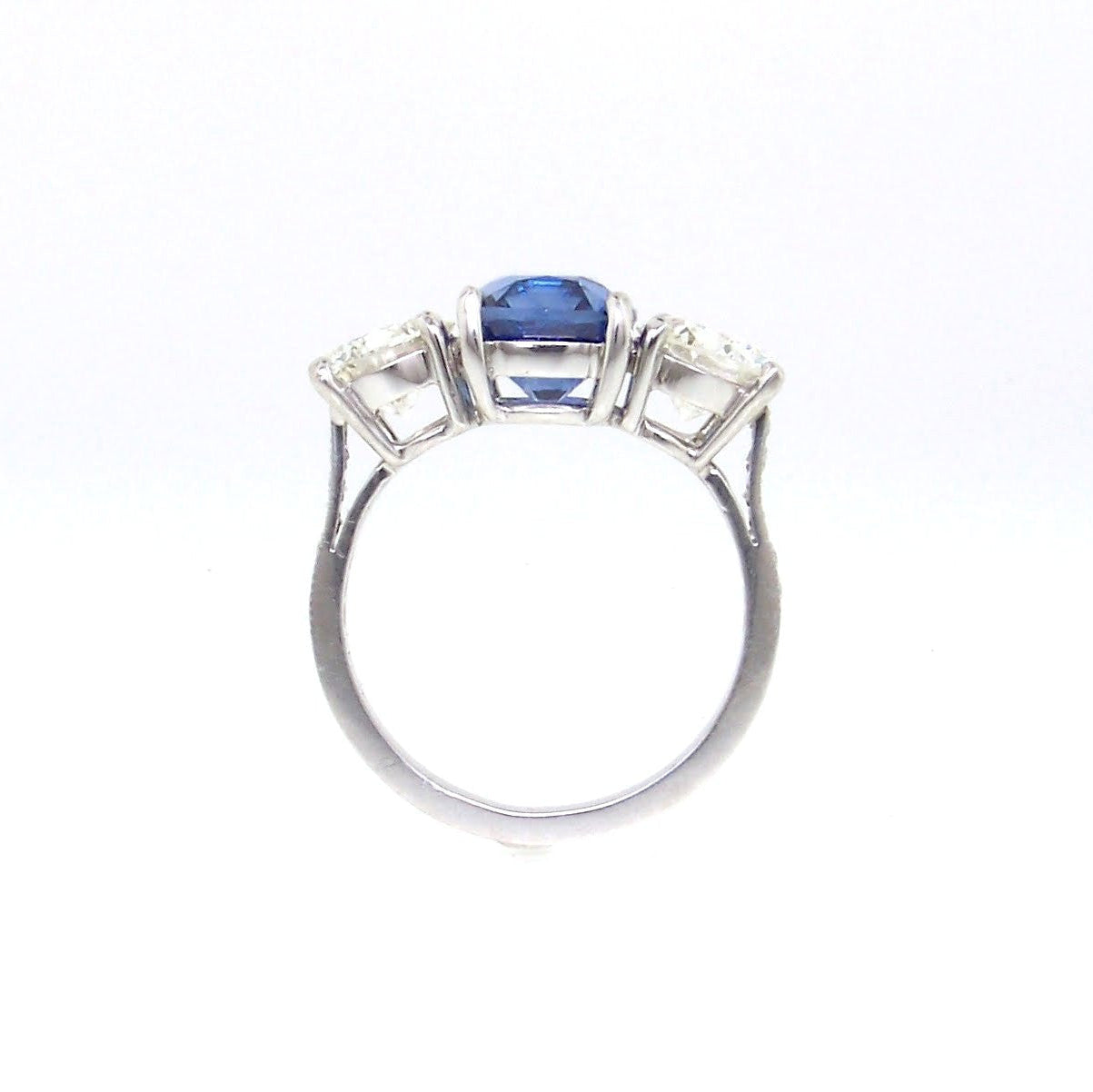 A platinum ring with a central sapphire stone and side diamonds, set in a classic prong setting.