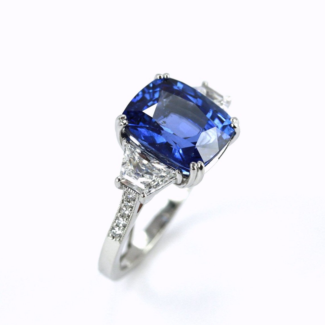 A platinum ring with a central sapphire stone and smaller diamonds set around the band.