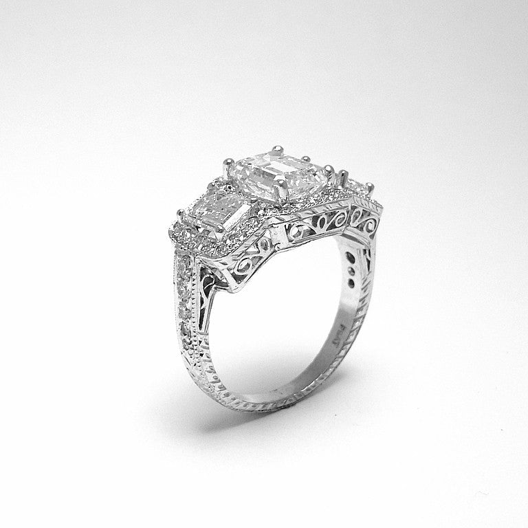 Platinum Three Stone Emerald Cut Diamond Ring with Round Diamond Halo