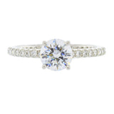A platinum round cut diamond ring with a clear centerpiece and additional pave diamonds set around the band.