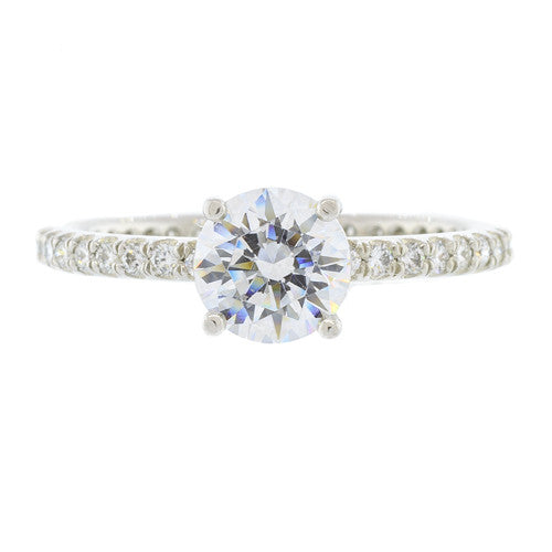 A platinum round cut diamond ring with a clear centerpiece and additional pave diamonds set around the band.