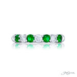 A JB Star platinum band ring with round diamonds and emeralds alternate placement